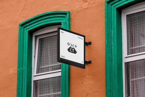 Square sign mockup on an orange building with green trimmings, displaying pixel art style logo, perfect for branding presentation.